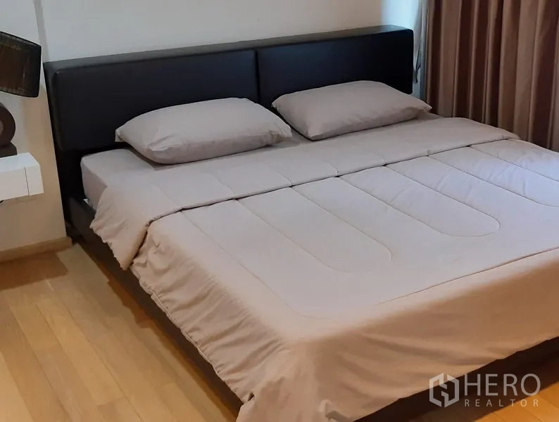 คอนโด ให้เช่าในKhlong Toei, Bangkok - ห้องนอนอบอุ่น เตียงคิงไซซ์ หัวเตียงบุหนัง พื้นไม้ และผ้าม่านกันแสง