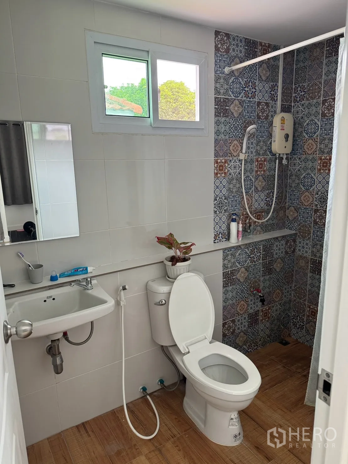 Detached House for rent in Saphan Sung, Bangkok - Bathroom with patterned tiles around the shower, electric water heater, sink, and toilet.