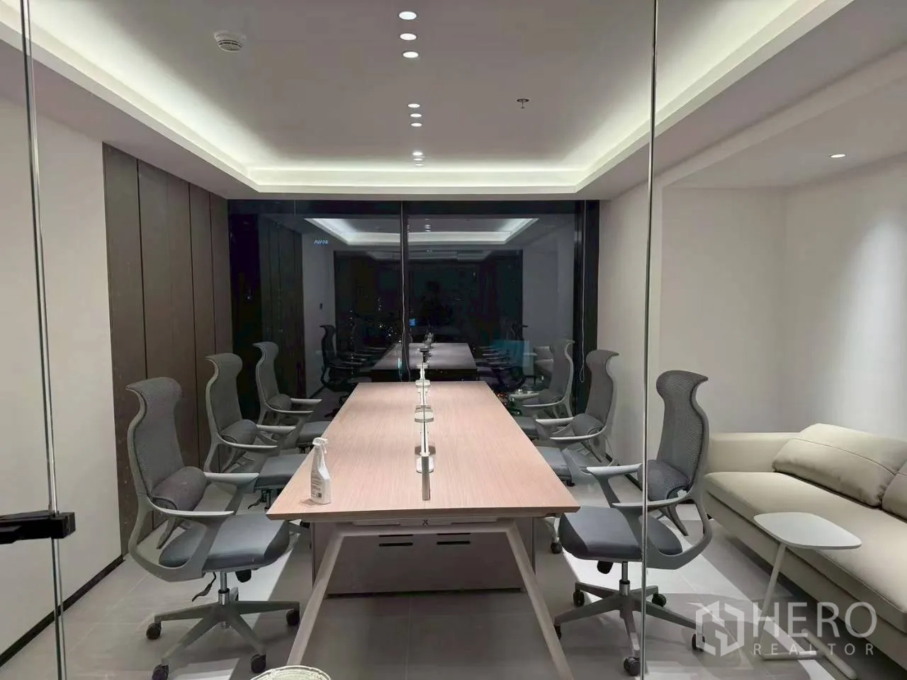 办公室 for rent in Din Daeng, Bangkok - 玻璃会议室，配长桌、人体工学椅及一张沙发。