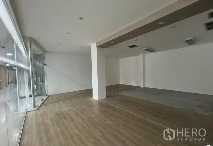 พื้นที่ขายปลีก ให้เช่า - มุมมองพื้นที่ร้าน พื้นลายไม้ ไฟฝังฝ้า และผนังกระจกตรงมุมสำหรับโชว์สินค้า