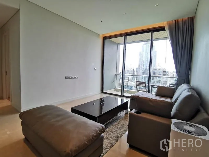 Condominium for rent in Pathum Wan, Bangkok - Living area facing the balcony with abundant natural light and downtown views.