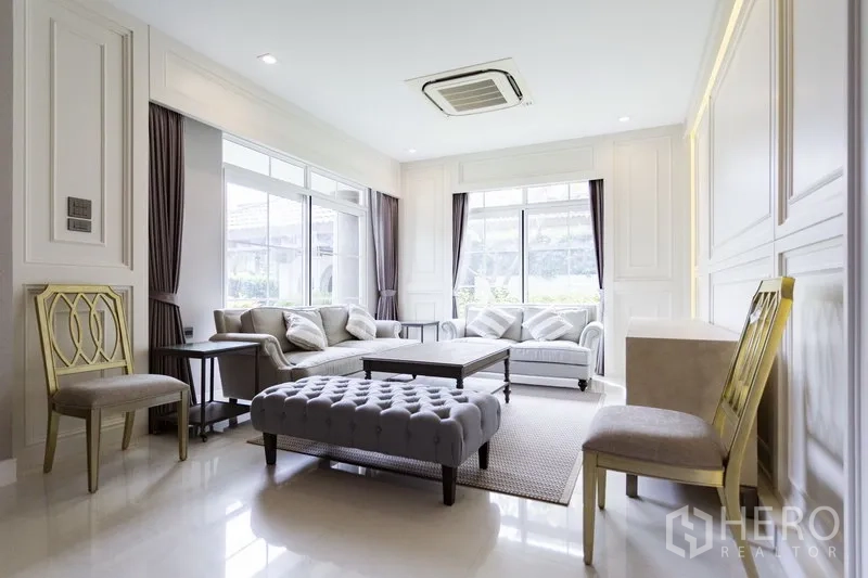 独立式住宅 出租在Mueang Samut Prakan, Samut Prakan - 采光充足的客厅，大窗、成套沙发与吊顶风管空调。