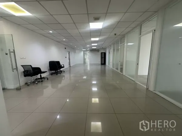 Office Space for rent in Huai Khwang, Bangkok - Long open workspace with swivel chairs, glass-fronted offices and polished tiled floor.