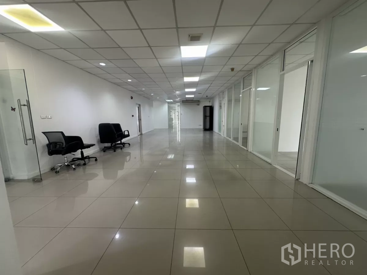 Office Space for rent in Huai Khwang, Bangkok - Long open workspace with swivel chairs, glass-fronted offices and polished tiled floor.