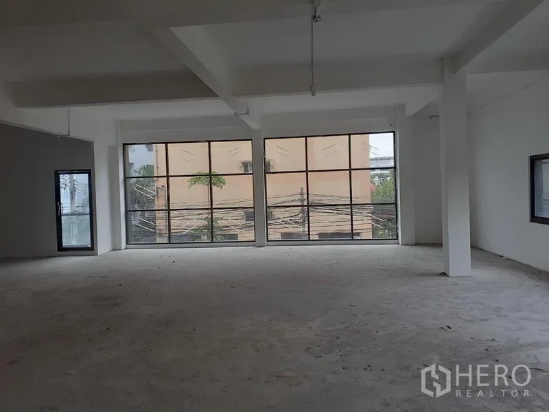 Office Space for rent in Khlong Toei, Bangkok - Bright shell‑and‑core office with two full‑height grid windows and a side glass door.
