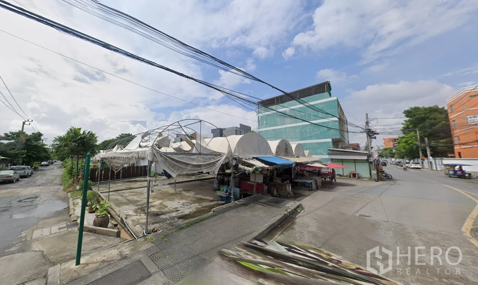 Land for sale in Bang Kapi, Bangkok - Covered market structures and side street access beside the development site.