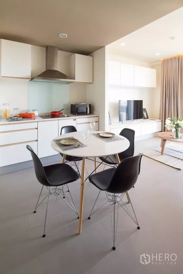 公寓 出租在Watthana, Bangkok - 开放式白色橱柜厨房与餐桌，旁连明亮客厅