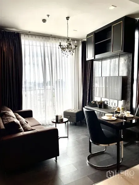 คอนโด ให้เช่าในWatthana, Bangkok - มุมนั่งเล่นโปร่งด้วยผ้าม่านสูงชนเพดาน โคมระย้า โซฟา และระเบียงเห็นวิวเมือง