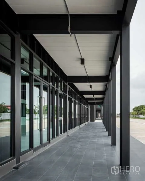 คลังสินค้า ให้เช่า - ระเบียงทางเดินหน้าทางเข้าออฟฟิศแบบกระจก ครอบด้วยกันสาด มองเห็นลานจอดรถกว้าง