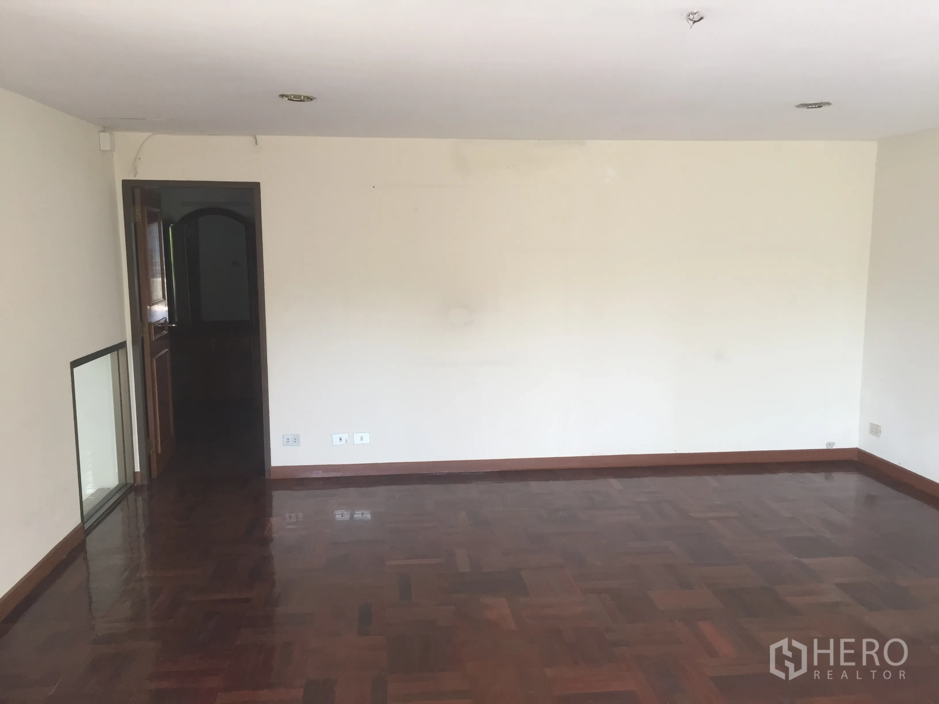 สำนักงานที่บ้าน ขายในWatthana, Bangkok - ห้องโล่ง พื้นไม้ปาร์เกต์เงา ผนังสีขาว และประตูไม้.