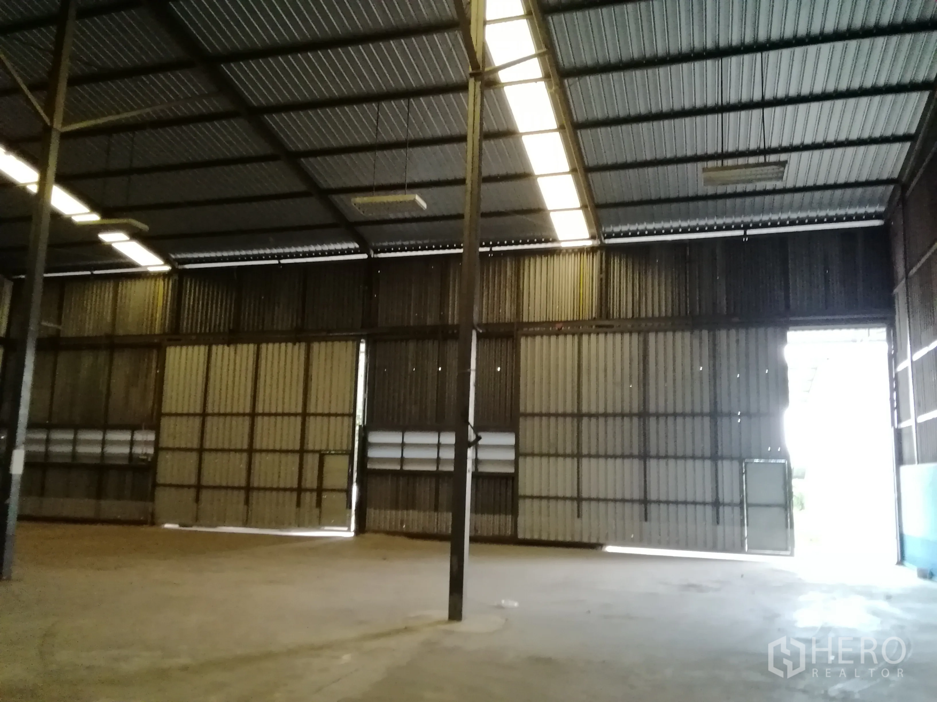 คลังสินค้า ให้เช่าในLam Luk Ka, Pathum Thani - ภายในโกดังเพดานสูง โครงเหล็ก แผ่นหลังคาโปร่งแสง พื้นคอนกรีต และประตูบานสไลด์ขนาดใหญ่.