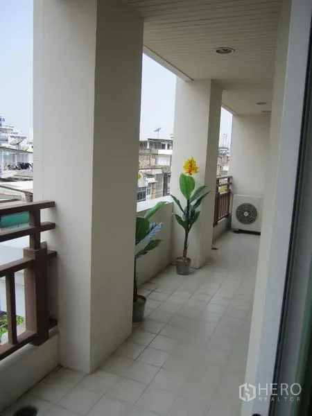 คอนโด ให้เช่าในBang Rak, Bangkok - ระเบียงยาวแบบมีหลังคา มองเห็นเมือง มีราวกันตก กระถางต้นไม้ และคอยล์แอร์ติดตั้งภายนอก