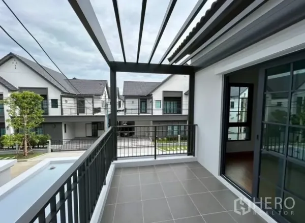 独立式住宅 出租在Bang Phli, Samut Prakan - 二层带遮阳格栅的露台，金属栏杆，可眺望社区景观。