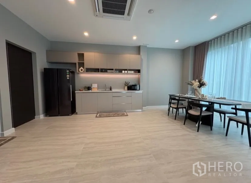 Detached House for rent in Suan Luang, Bangkok - Open-plan dining area and pantry kitchen with tall windows and modern cabinetry.