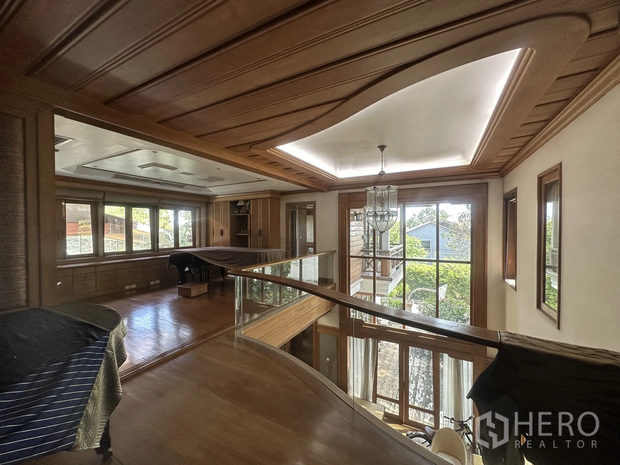 Detached House for rent in Lam Luk Ka, Pathum Thani - Upper landing with glass balustrade, chandelier, and tall windows to garden views.