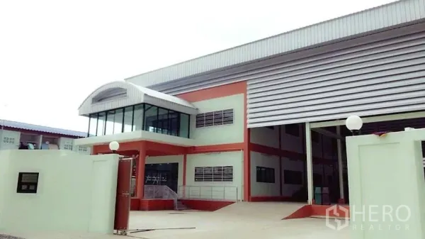 โรงงาน ขายในPathum Thani - ด้านหน้าโรงงานสมัยใหม่พร้อมออฟฟิศกระจกมุมอาคารและประตูม้วนขนาดใหญ่