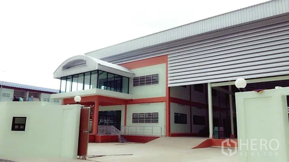 โรงงาน ขายในPathum Thani - ด้านหน้าโรงงานสมัยใหม่พร้อมออฟฟิศกระจกมุมอาคารและประตูม้วนขนาดใหญ่