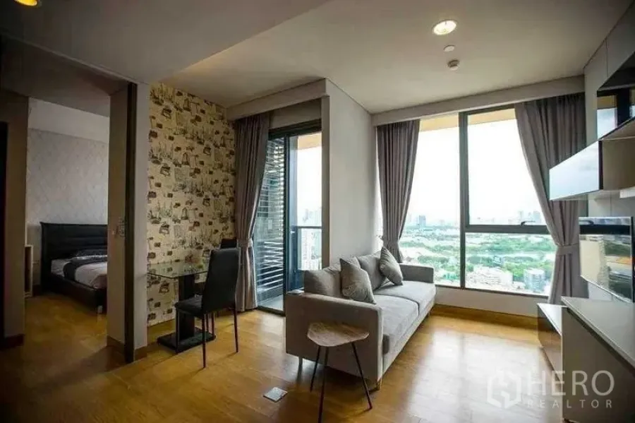 公寓 出租在Khlong Toei, Bangkok - 开放式起居区连接卧室，带阳台和落地窗景。