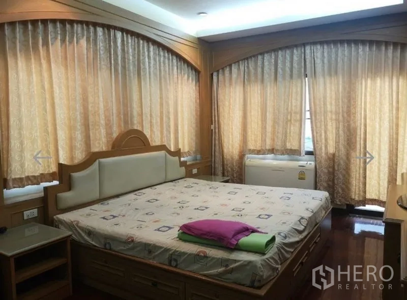 Detached House for sale in Khlong San, Bangkok - Primary bedroom with a large bed, wood built-ins and full-length curtained windows.