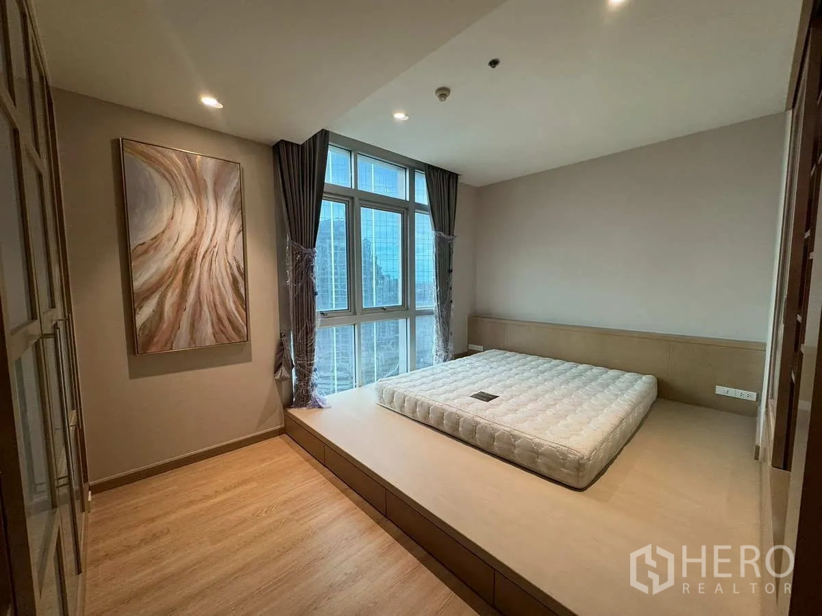 Condominium for rent or sale in Khlong Toei, Bangkok - Bedroom with platform bed, large windows and abstract artwork.
