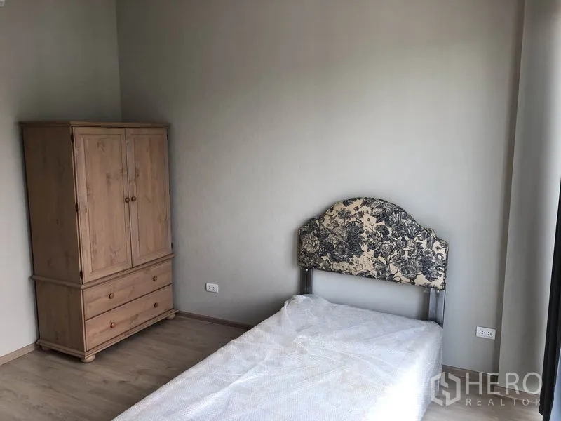 Townhouse for rent in Suan Luang, Bangkok - Bedroom corner with wooden wardrobe and single bed.