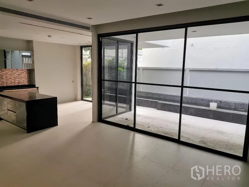 Detached House for sale in Wang Thonglang, Bangkok - Open-plan living and dining area with expansive sliding glass doors to a private courtyard.