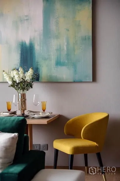 公寓 出租或出售在Bang Rak, Bangkok - 餐角特写，黄色餐椅、抽象画与双人餐具摆设。