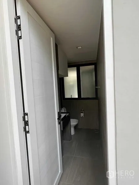 Home Office for sale in Wang Thonglang, Bangkok - Compact guest bathroom finished in grey tiles with window, sink and toilet.