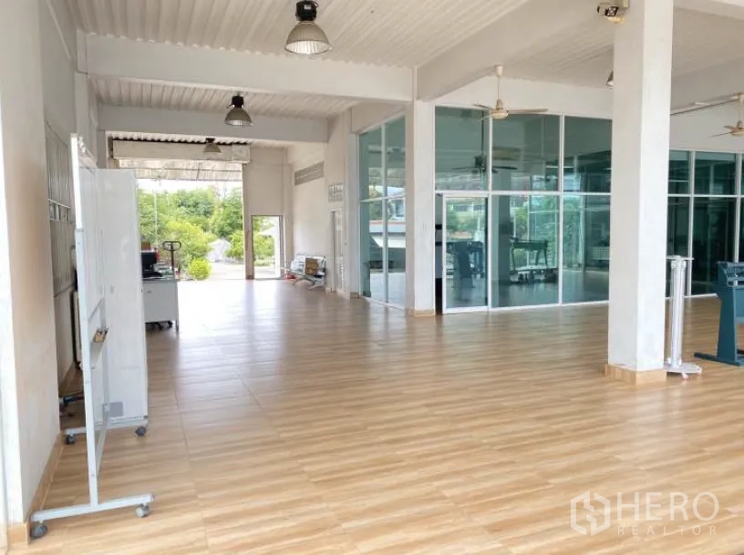 Land for sale in Lat Krabang, Bangkok - Open-plan showroom interior with glass partitions, high ceiling, lighting, and tiled flooring.