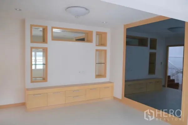 ทาวน์เฮาส์ ให้เช่าในKhlong Toei, Bangkok - ห้องพักผ่อนมีชั้นวางทีวีไม้โทนอ่อนและกระจกบานใหญ่กรอบไม้