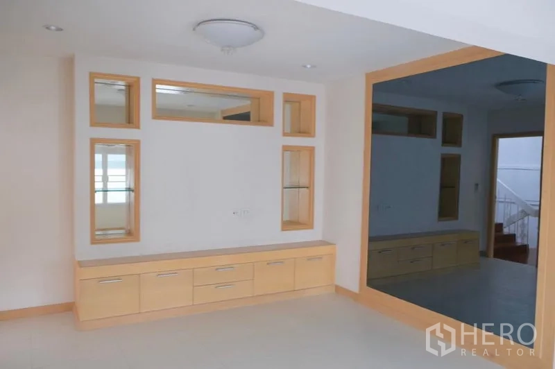 ทาวน์เฮาส์ ให้เช่าในKhlong Toei, Bangkok - ห้องพักผ่อนมีชั้นวางทีวีไม้โทนอ่อนและกระจกบานใหญ่กรอบไม้