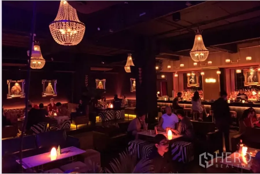 零售空间 出租在Watthana, Bangkok - 氛围灯光的休闲区，水晶吊灯、白色桌面与斑马纹座椅。