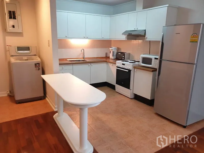 คอนโด ให้เช่าในWatthana, Bangkok - ครัวรูปตัวแอลตู้สีขาว พร้อมเตาอบ ไมโครเวฟ ตู้เย็น และเครื่องซักผ้า