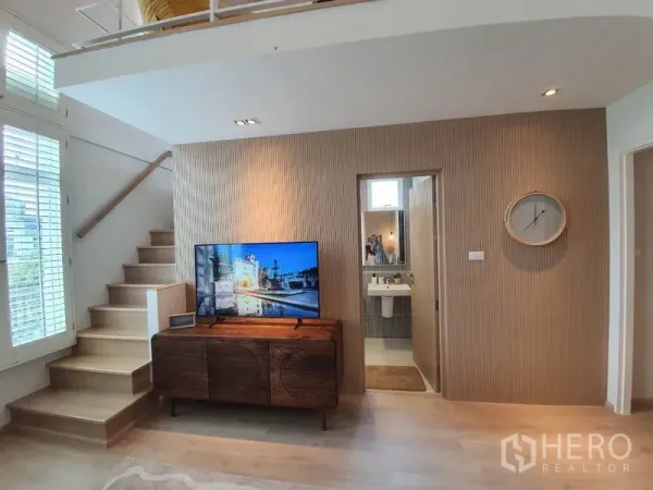 Detached House for rent in Prawet, Bangkok - Family room with staircase to mezzanine, TV console and adjacent bathroom.