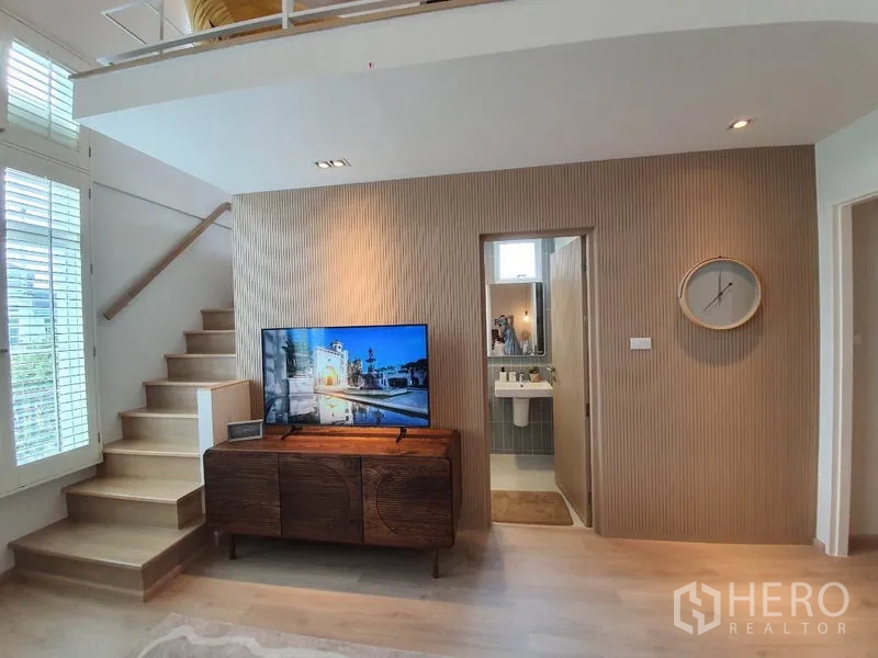 Detached House for rent in Prawet, Bangkok - Family room with staircase to mezzanine, TV console and adjacent bathroom.