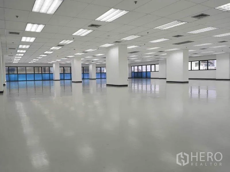 办公空间 出租在Phaya Thai, Bangkok - 柱网清晰的办公室，蓝色隔热玻璃窗、日光灯与中央空调出风口。