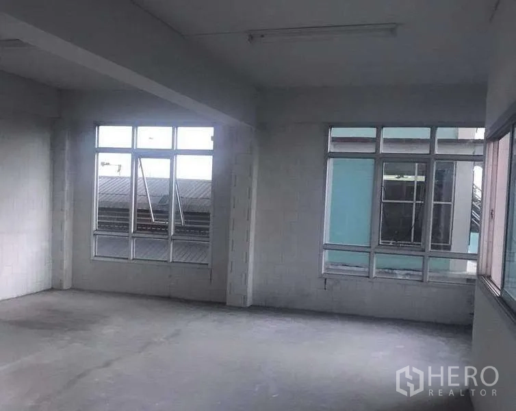 Warehouse for rent in Pathum Thani - Spacious upper-floor room with large grid windows and concrete floor for office use
