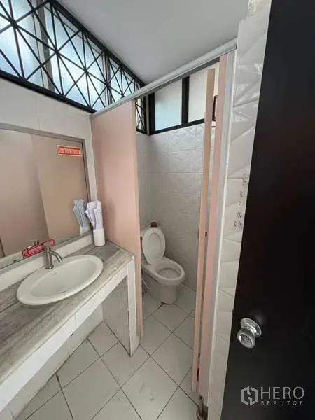 Office Space for rent in Khlong Toei, Bangkok - Clean restroom with a sink, mirror and a toilet stall.