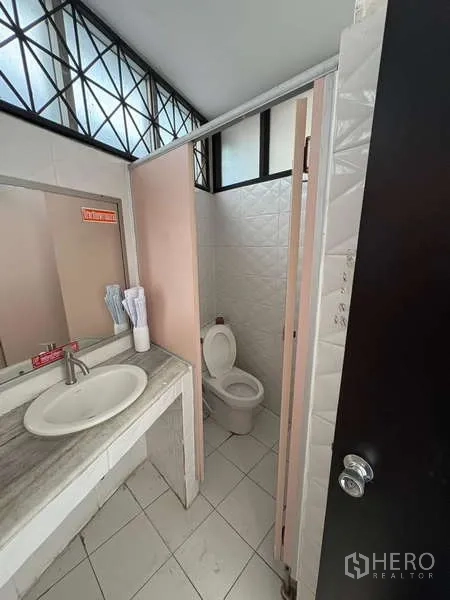 Office Space for rent in Khlong Toei, Bangkok - Clean restroom with a sink, mirror and a toilet stall.
