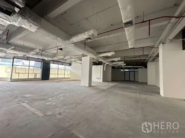 办公空间 出租 - 大面积空置办公楼层一角，结构柱与包覆空调管道，采光良好。