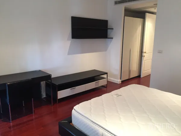 Condominium for rent in Pathum Wan, Bangkok - Bedroom with polished wood floors, work desk, wall shelving and built-in wardrobe.