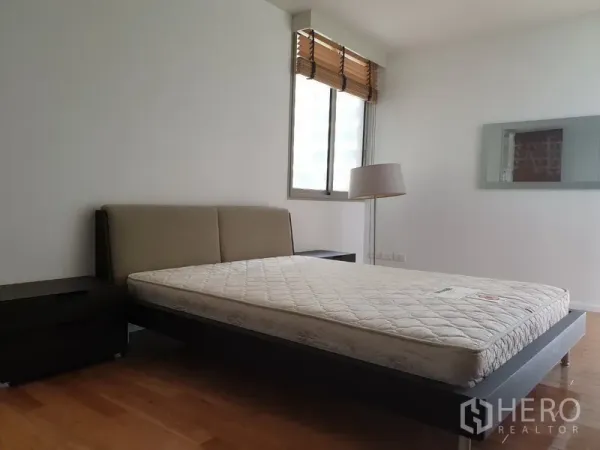 公寓 出租在Bang Rak, Bangkok - 明亮主卧，平台床、床头柜、落地灯与百叶窗，位于Silom的The Legend Saladaeng。