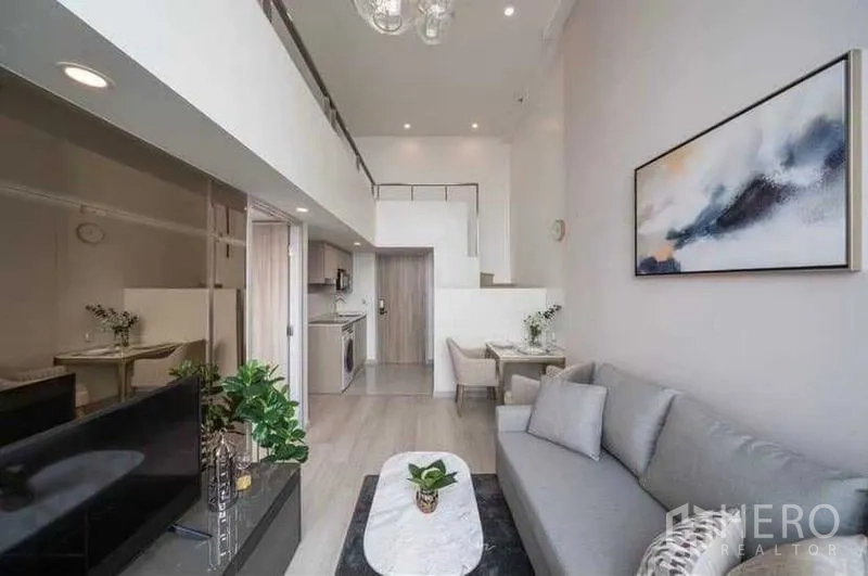 Condominium for rent in Sathon, Bangkok - Living area facing entry, pantry and dining under a loft ceiling.