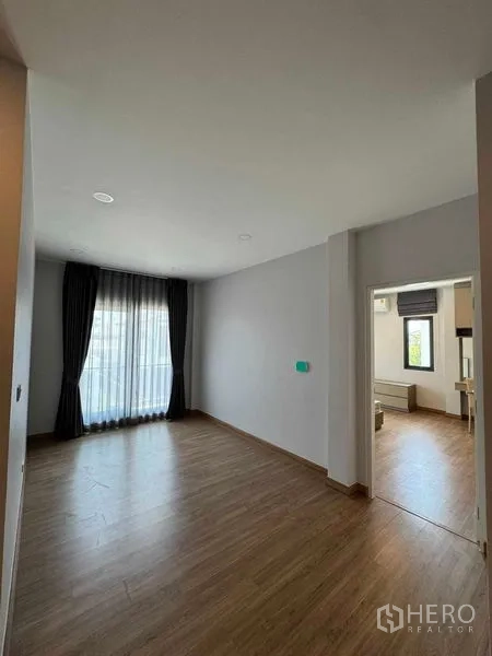 Detached House for rent in Don Mueang, Bangkok - Bright empty living space with wood flooring and floor-to-ceiling curtains.