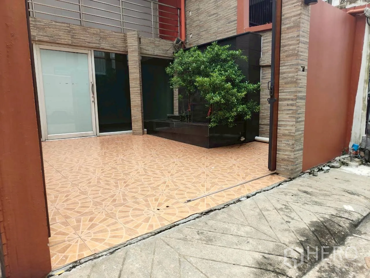 Home Office for rent in Watthana, Bangkok - Gated front courtyard with patterned tiles and planter feature.