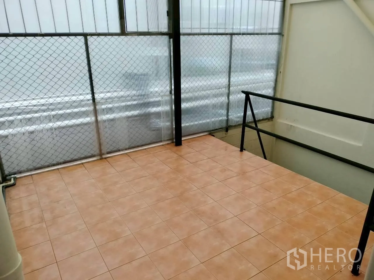 Home Office for rent in Watthana, Bangkok - Covered terrace with tiled floor and safety mesh railing.