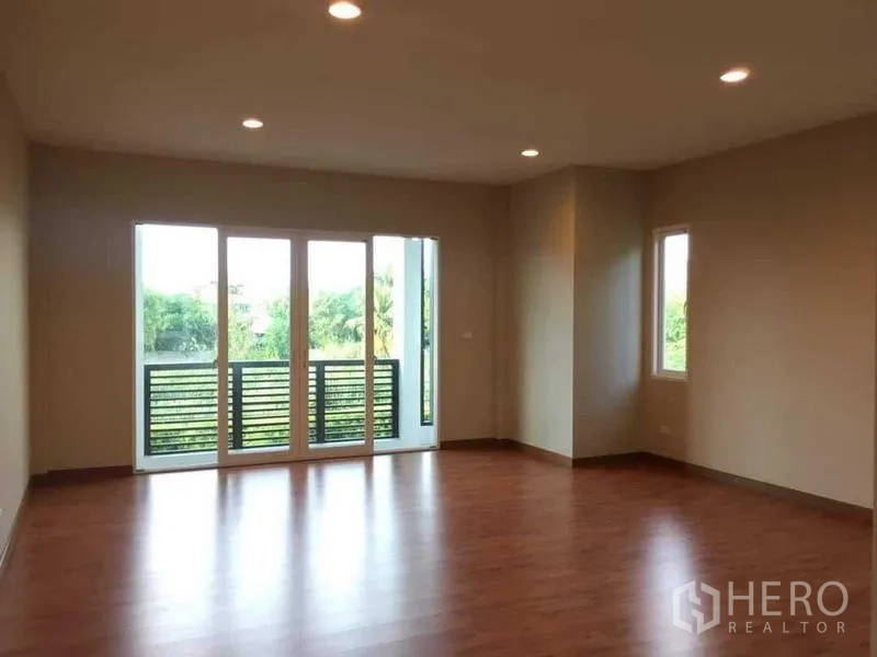 独立式住宅 出售在Bang Kruai, Nonthaburi - 二楼卧室，木地板、嵌灯与通往阳台的玻璃门。