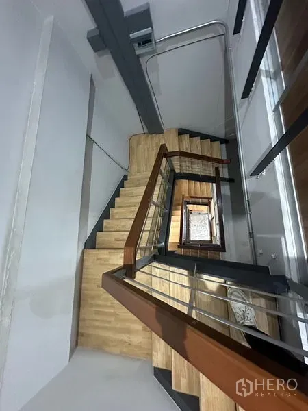 Home Office for rent in Phra Khanong, Bangkok - Stairwell with wooden steps, metal railing and a multi-story view.