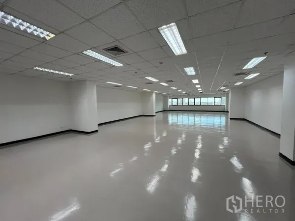 Office Space for rent or sale - Wide view of bright office space with polished flooring, acoustic ceiling, and city-facing windows.