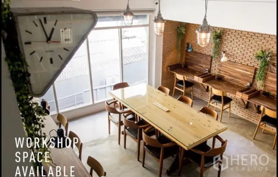 Home Office for rent in Khlong Toei, Bangkok - Bright coworking room with a long wooden table, brick feature wall, pendant lights and large windows.